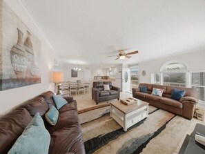 A spacious living room with two sofas, a coffee table, and a dining area in the background.