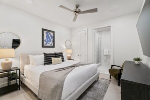 A modern bedroom with a bed, bedside tables, a ceiling fan, a framed artwork, and a door leading to another room. - The Theodore 5BD/5B - Combo Unit - 605/606 (New Orleans)