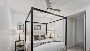 Ein modernes Schlafzimmer mit Himmelbett, Nachttischlampen und Deckenventilator.