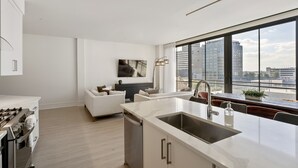 Eine moderne Küche mit einem großen Fenster, einem Essbereich mit einer Couch und Blick auf die Stadt.