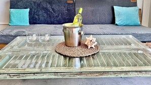 Une table en verre sur laquelle se trouvent une bouteille de champagne, deux verres à vin et un coquillage décoratif.