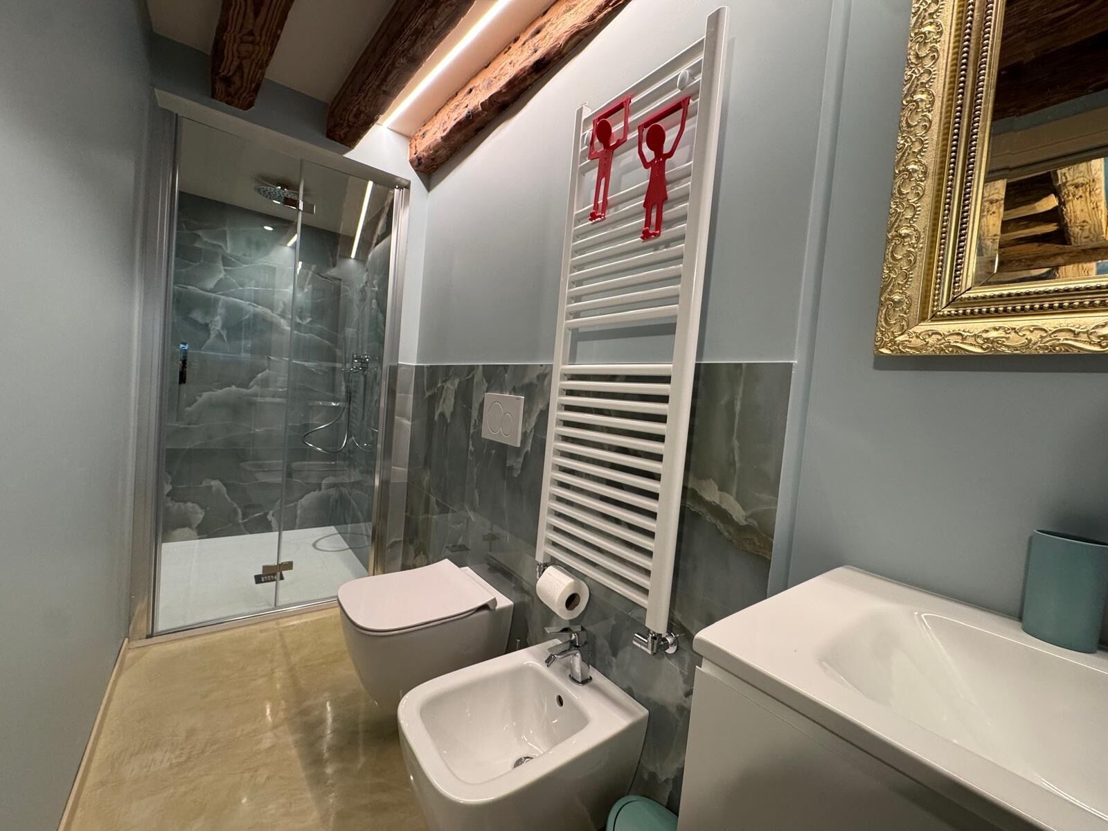 Een badkamer met een douchecabine van glas, een bidet, een toilet en een wastafel.