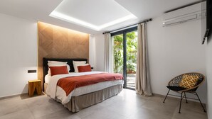 Une chambre moderne avec une lucarne, un lit avec une literie rouge et blanche, une tête de lit en bois et une vue sur la verdure à l’extérieur.