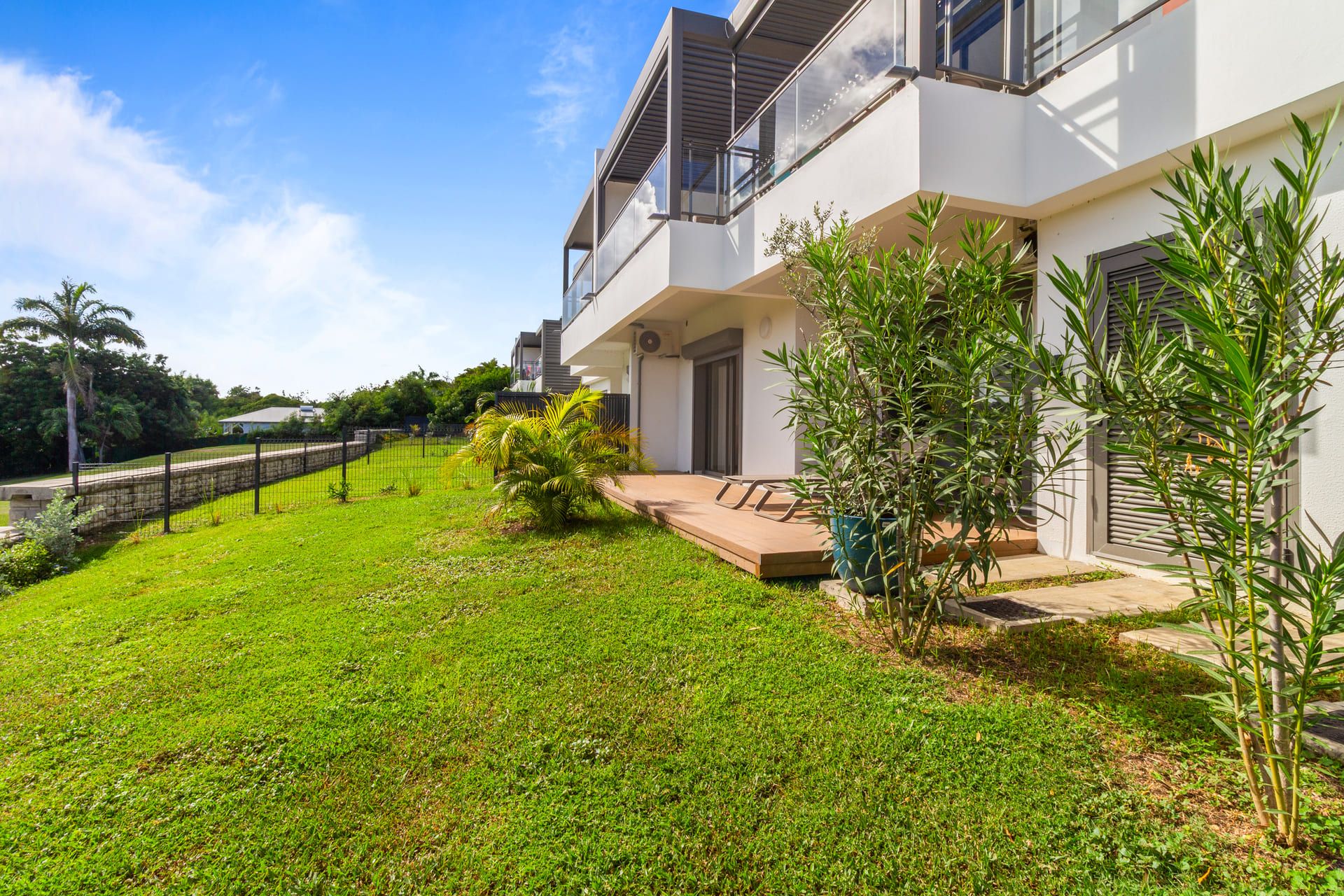 Een modern woonhuis met twee verdiepingen, een verzorgd gazon en diverse planten.