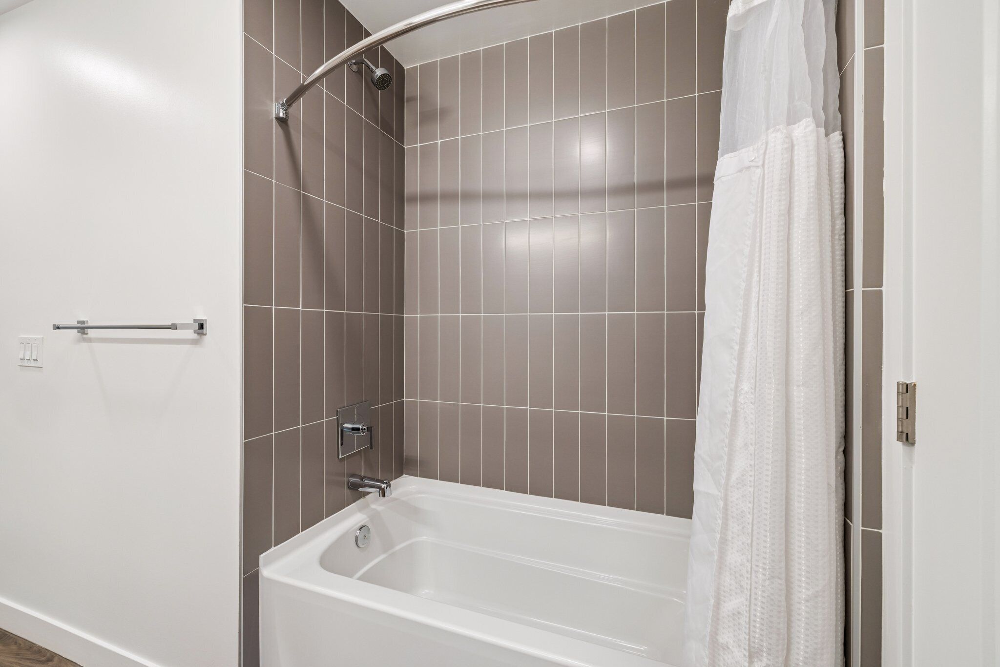 A modern bathroom with a bathtub, shower, and a towel rack.