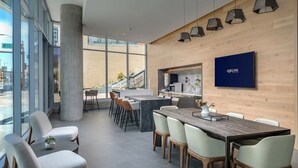 A modern hotel lobby with a large dining area, a kitchen, and a large window offering a city view. - CozySuites at ADELINE (Phoenix)