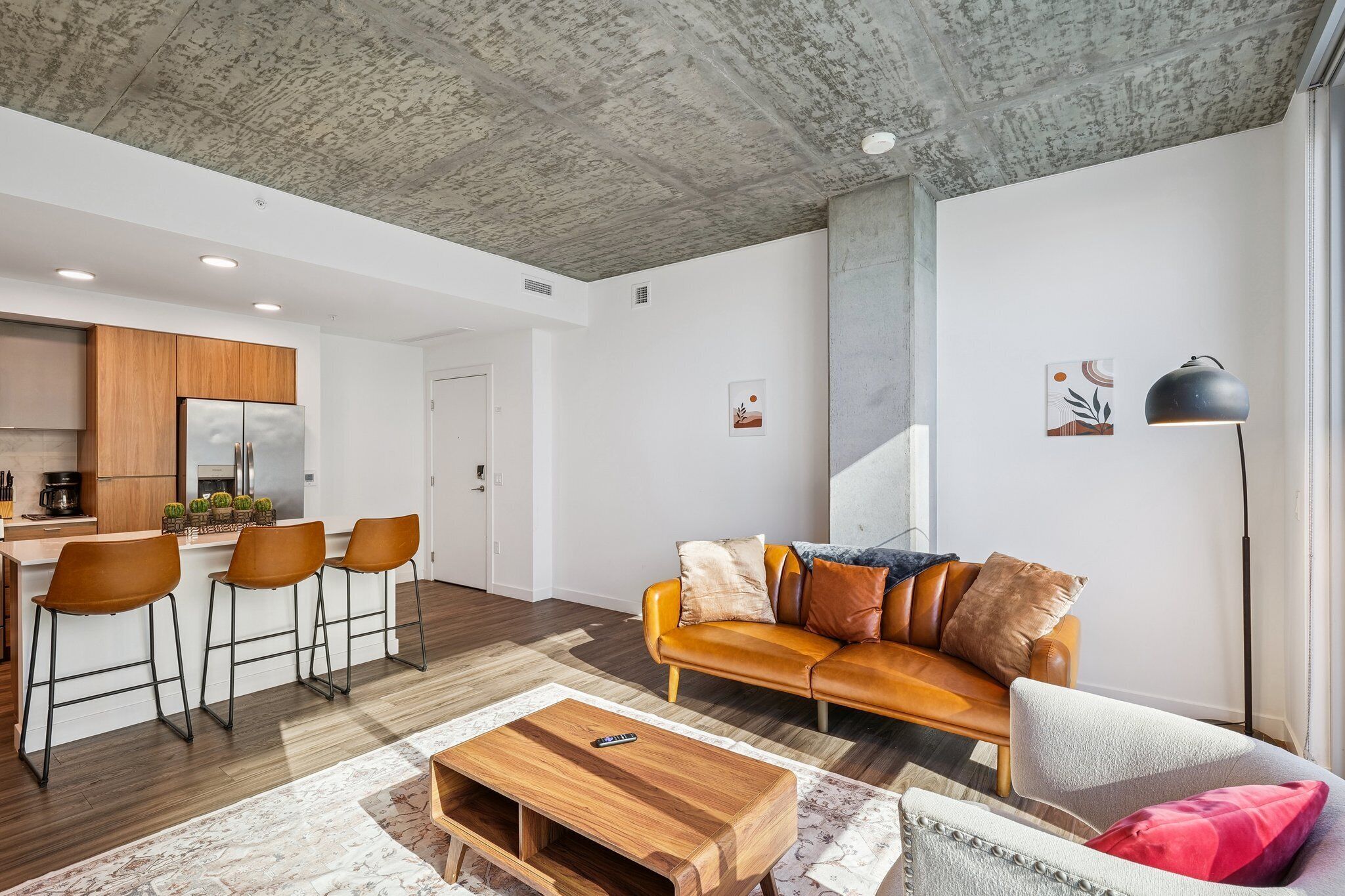 A modern living room with a leather sofa, wooden coffee table, and a bar area with stools.