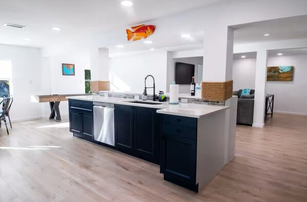 Eine moderne Küche mit einer zentralen Kochinsel, dunklen Schränken und einer großen Fischdekoration an der Wand.