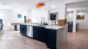 Una cocina moderna con una isla central, muebles oscuros y un salpicadero.