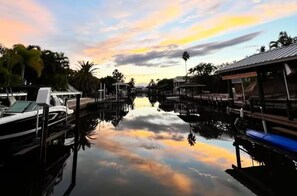 Uma marina com barcos atracados, águas calmas e céu ao pôr do sol.