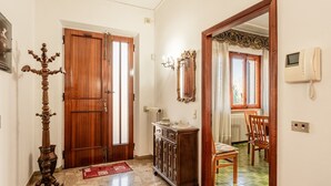 Un pasillo con puerta de madera, un armario, un espejo, un teléfono y una silla.