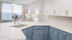 Une cuisine moderne dotée d’un grand îlot central, de meubles blancs et offrant une vue sur l’extérieur.