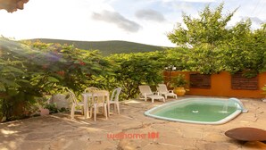 Un jardin avec une piscine, des chaises d’extérieur et une végétation luxuriante.