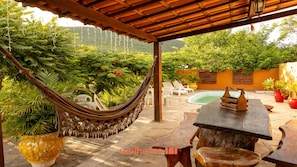 A hammock, outdoor seating, a pool, and lush greenery.