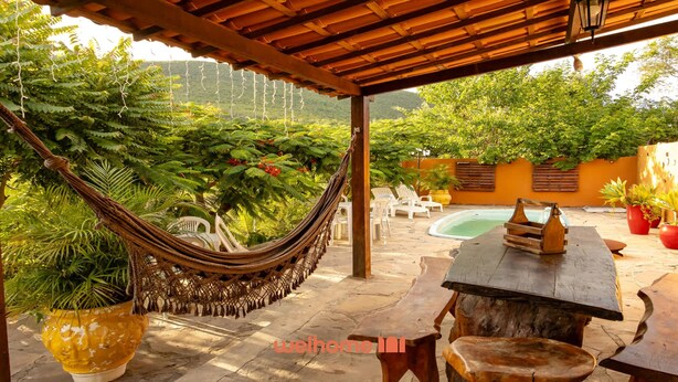 Un hamac sous une pergola en bois, une piscine et des sièges d’extérieur.