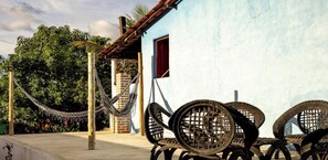 A building with a blue exterior, a hammock, and metal chairs.