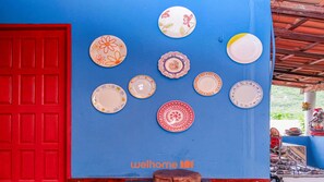 A blue wall with various decorative plates and a red door.