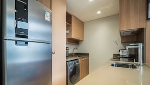 Een moderne keuken met roestvrijstalen apparatuur, houten kastjes en een ingebouwde wasmachine en droger.