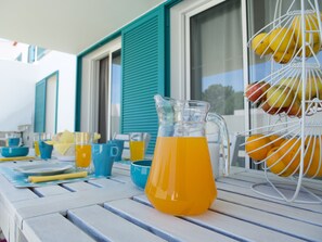 Et bord med en kande appelsinjuice, en frugtkurv samt diverse kopper og skåle.