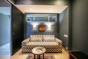 A modern living room with a patterned sofa, a glass coffee table, and a wall-mounted light fixture. - Casa Lussienez | Luxury Ocean-View 3BR @ Paramount (Puerto Vallarta)