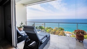 Ein Balkon mit Meerblick, einem Blumentopf und zwei Stühlen.