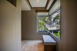 A modern interior with a bench, a window, and a view of a building with balconies. - Casa Lussienez | Luxury Ocean-View 3BR @ Paramount (Puerto Vallarta)