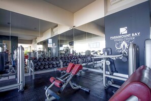 A gym with weightlifting equipment, mirrors, and a wall with the text 'PARAMOUNT BAY FITNESS CENTER'. - Casa Lussienez | Luxury Ocean-View 3BR @ Paramount (Puerto Vallarta)