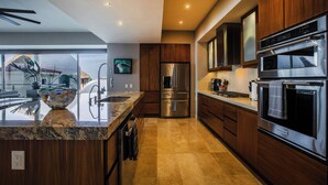 Eine moderne Küche mit Edelstahlgeräten, Holzschränken und einer Arbeitsplatte aus Granit.