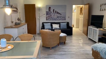 En moderne stue med sofa, stole, spisebord og fjernsyn.
