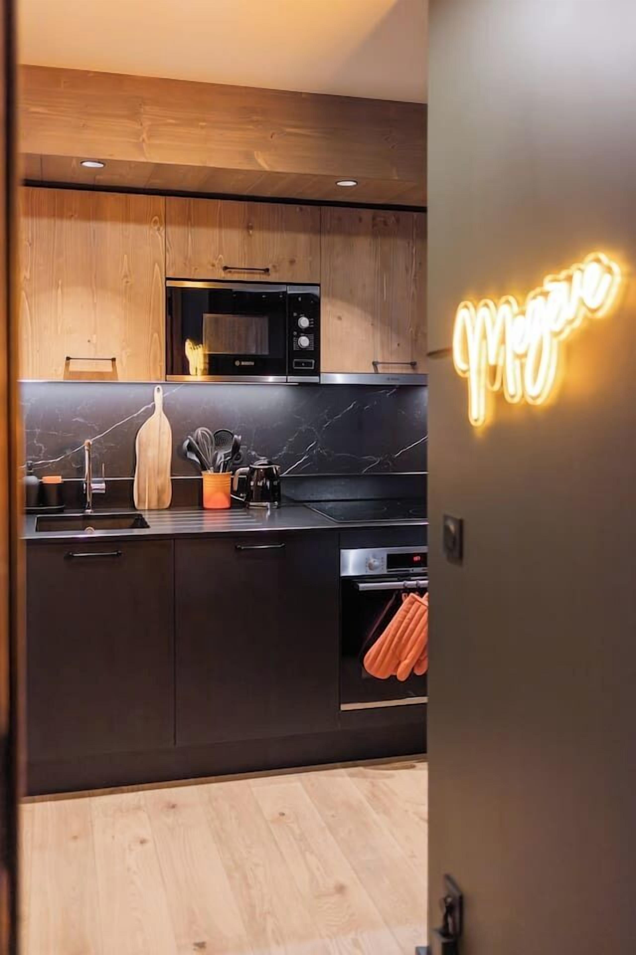 A modern kitchen with dark cabinetry, a microwave, and a neon sign.