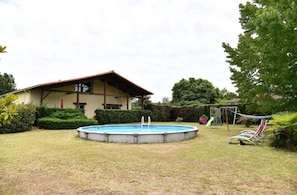A house with a swimming pool, a covered patio, and a playground.