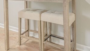 Una mesa de madera con un banco, un espejo redondo y un termostato en la pared.