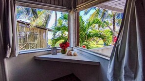 Een kamer met een raam dat uitkijkt over een omheind buitengebied met palmbomen.