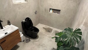 Kylpyhuone, jossa on wc, pesuallas ja ruukussa oleva kasvi.