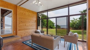 A modern room with large windows, a ceiling fan, and wicker furniture.