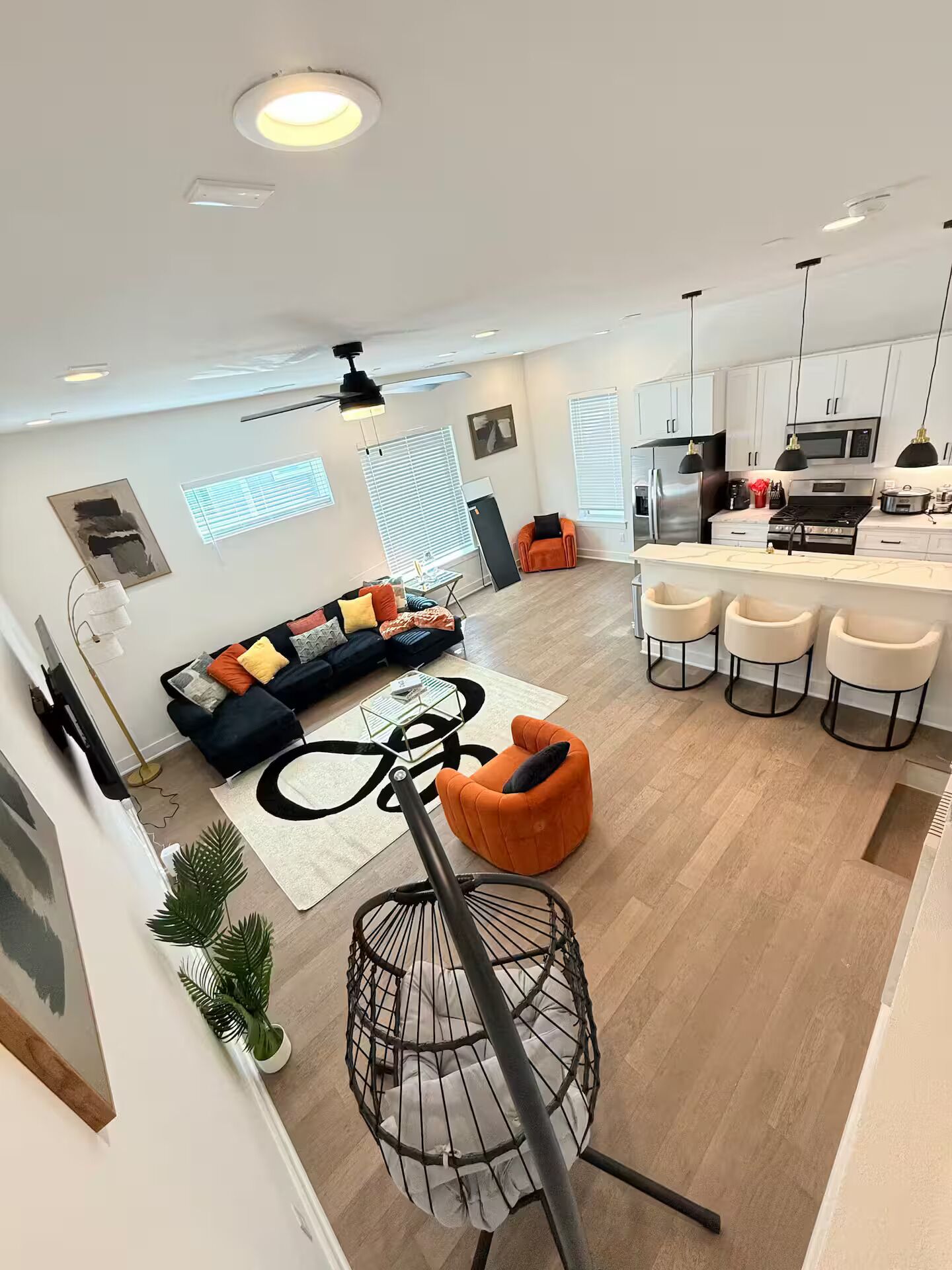 A modern living room with a sofa, a dining area with bar stools, and a kitchen with a microwave and stove.