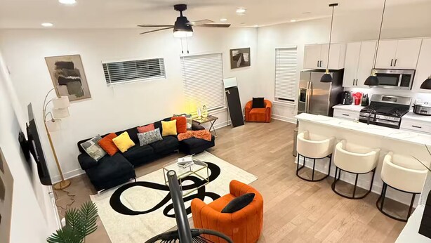 A modern living room with a black and orange sofa, a coffee table, and a hanging chair. - 3-bedroom house in serene Houston with cool AC for relaxing stays (Houston)