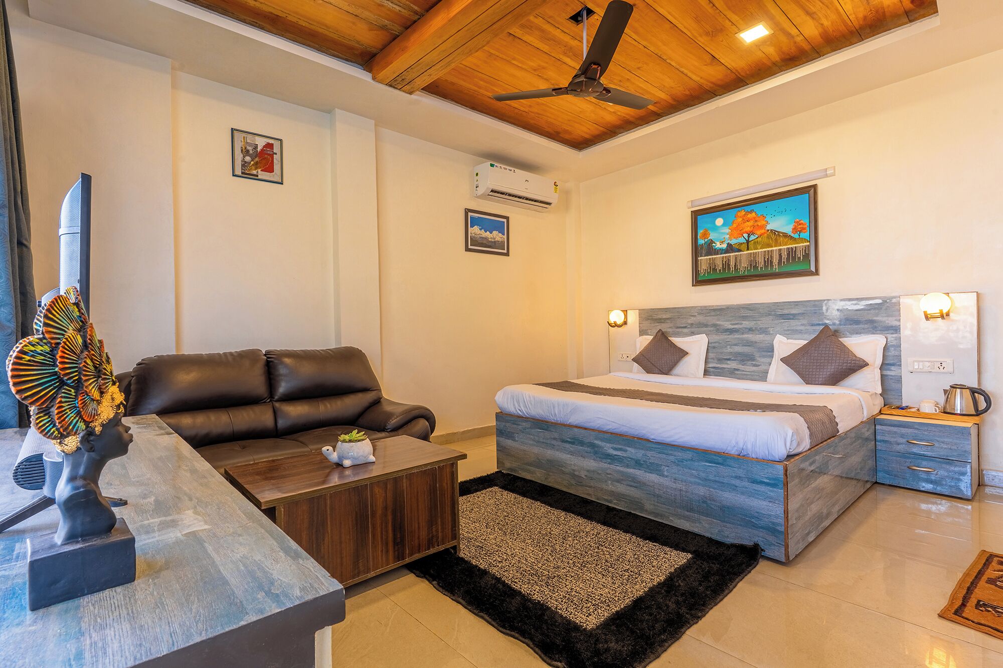 A bedroom with a bed, a sofa, a coffee table, and a ceiling fan.
