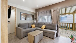 Una sala de estar moderna con un sofá seccional, una mesa de centro de madera y un ventanal con cortinas.