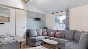 Ein modernes Wohnzimmer mit einer Couch, einem kleinen Tisch und einem Essbereich mit Stühlen und einem Tisch für zwei Personen.
