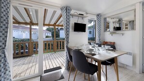 Ein Essbereich mit Tisch, Stühlen, einem Fernseher und Blick ins Freie.