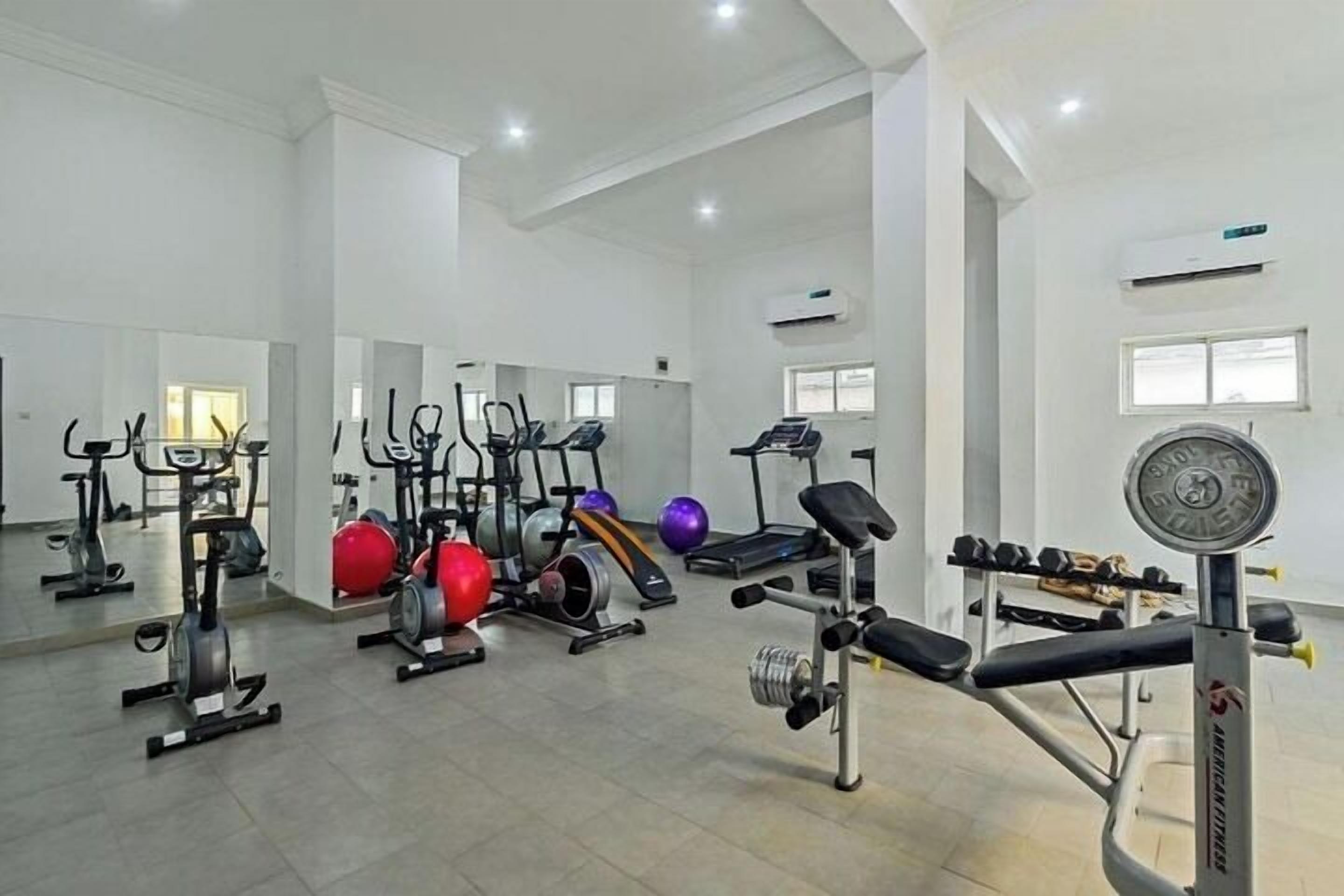Ett gym med olika typer av träningsutrustning, inklusive löpband, motionscyklar och styrketräningsmaskiner.