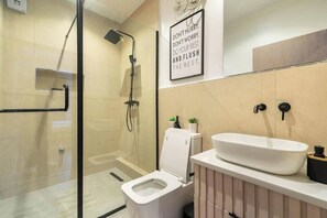 A modern bathroom with a glass-enclosed shower, a white toilet, and a sink with a large basin. - Glitaz Apartment (Abuja)