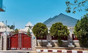 A building with a red gate, a blue roof, and a stone wall. - Glitaz Apartment (Abuja)