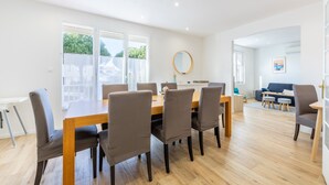 A dining area with a wooden table and chairs, a round mirror, and a view of the outdoors. - Family home in central Fromentine with terrace, Wi-Fi, air conditioning, €800 security deposit (La Barre-de-Monts)