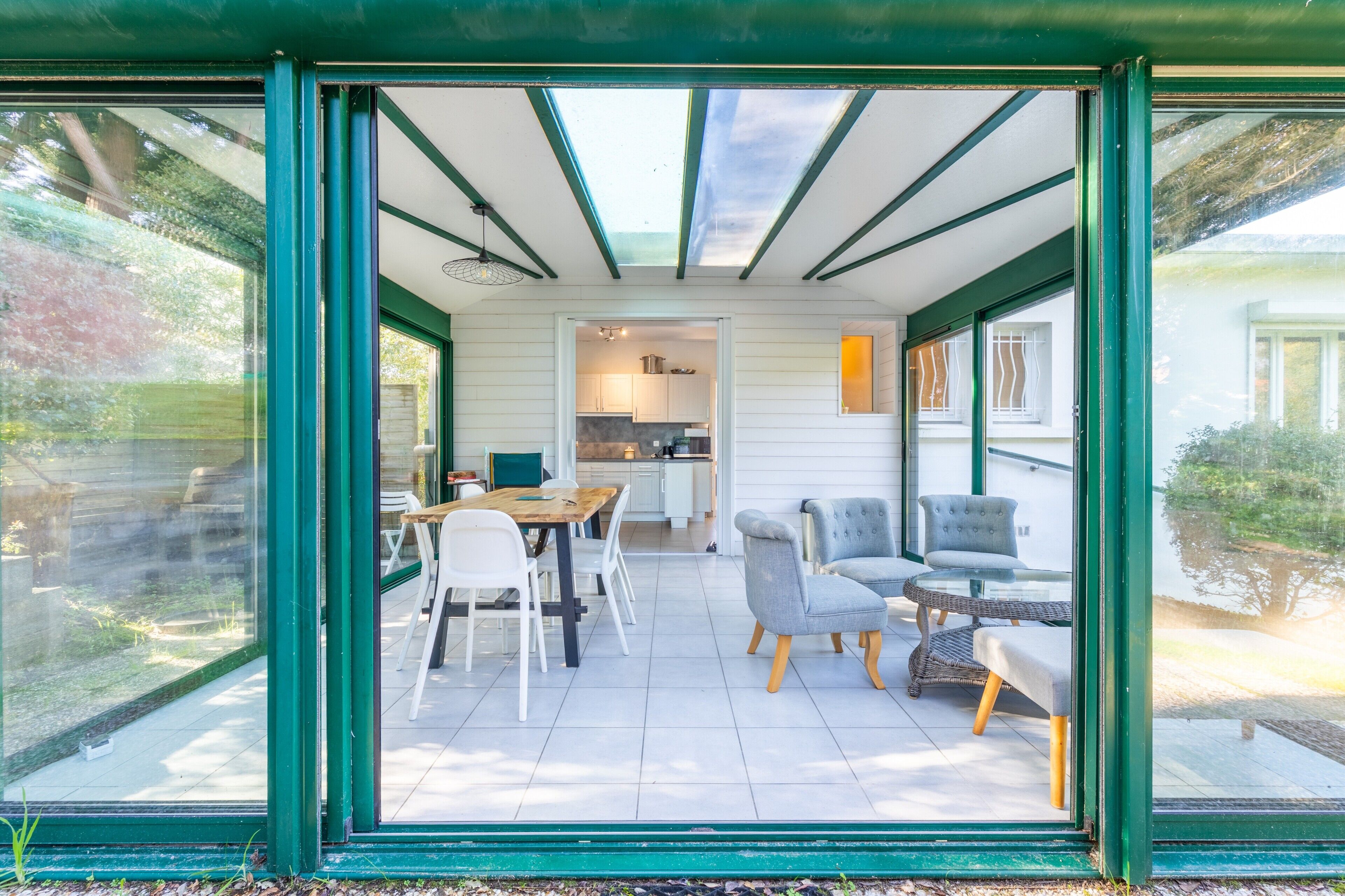 Een moderne keuken met witte kasten, een eethoek met witte stoelen, en een zithoek met een bank en stoelen.