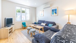 A modern living room with a sofa, TV, and a small table. - Family home in central Fromentine with terrace, Wi-Fi, air conditioning, €800 security deposit (La Barre-de-Monts)
