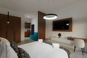 A modern hotel room with a large bed, a desk, a TV, and a wardrobe.