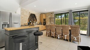 Een moderne keuken met een stenen muur, roestvrijstalen apparatuur, een bar en een uitzicht door grote ramen.