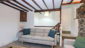 Una sala de estar acogedora con un sofá gris, una mesa de centro de madera y una pared de piedra.